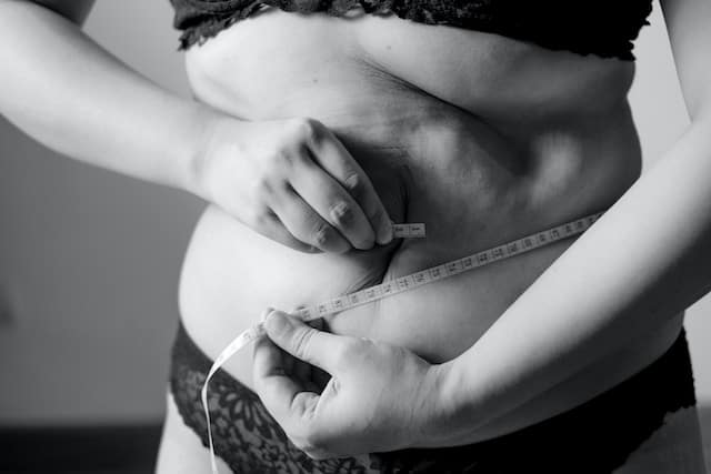 woman measuring her waistline