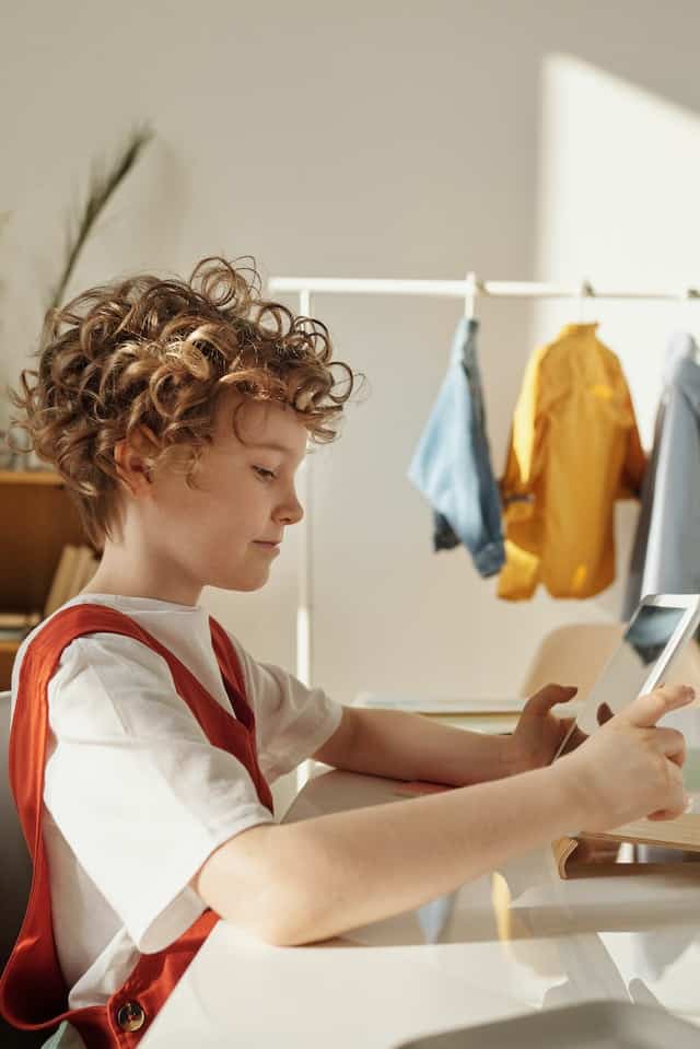 Boy in White and Red Polo Shirt Holding White Tablet Computer